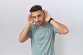 Hispanic man with beard standing over white background trying to hear both hands on ear gesture, curious for gossip Royalty Free Stock Photo