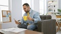 Hispanic man with beard using smartphone and holding cup in modern office setting Royalty Free Stock Photo