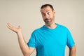 Hispanic man with a beard wearing a blue t-shirt in a skeptical attitude offering something in the palm of his hand Royalty Free Stock Photo