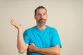 Hispanic man with a beard wearing a blue t-shirt in a skeptical attitude offering something in the palm of his hand Royalty Free Stock Photo