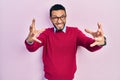 Hispanic man with beard wearing business shirt and glasses shouting frustrated with rage, hands trying to strangle, yelling mad Royalty Free Stock Photo