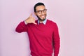 Hispanic man with beard wearing business shirt and glasses smiling doing phone gesture with hand and fingers like talking on the Royalty Free Stock Photo