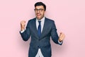 Hispanic man with beard wearing business suit and tie very happy and excited doing winner gesture with arms raised, smiling and Royalty Free Stock Photo