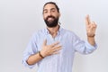 Hispanic man with beard wearing casual shirt smiling swearing with hand on chest and fingers up, making a loyalty promise oath Royalty Free Stock Photo