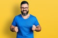 Hispanic man with beard wearing casual t shirt and glasses excited for success with arms raised and eyes closed celebrating Royalty Free Stock Photo