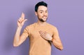 Hispanic man with beard wearing casual t shirt smiling swearing with hand on chest and fingers up, making a loyalty promise oath Royalty Free Stock Photo