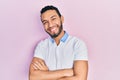 Hispanic man with beard wearing casual white t shirt happy face smiling with crossed arms looking at the camera