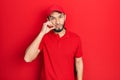 Hispanic man with beard wearing delivery uniform and cap mouth and lips shut as zip with fingers