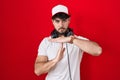 Hispanic man with beard wearing gamer hat and headphones doing time out gesture with hands, frustrated and serious face