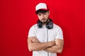 Hispanic man with beard wearing gamer hat and headphones looking sleepy and tired, exhausted for fatigue and hangover, lazy eyes