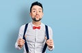 Hispanic man with beard wearing hipster look holding suspenders looking at the camera blowing a kiss being lovely and sexy Royalty Free Stock Photo