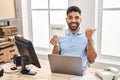 Hispanic man with beard working at the office with laptop holding thanks banner pointing thumb up to the side smiling happy with Royalty Free Stock Photo