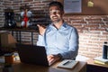 Hispanic man with beard working at the office at night smiling with happy face looking and pointing to the side with thumb up Royalty Free Stock Photo