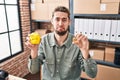 Hispanic man with beard working at small business ecommerce holding piggy bank and bitcoin depressed and worry for distress, Royalty Free Stock Photo