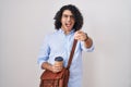 Hispanic man with curly hair drinking a cup of take away coffee pointing displeased and frustrated to the camera, angry and Royalty Free Stock Photo