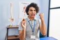 Hispanic man with curly hair holding cbd oil annoyed and frustrated shouting with anger, yelling crazy with anger and hand raised Royalty Free Stock Photo