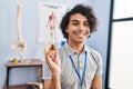 Hispanic man with curly hair holding cbd oil looking positive and happy standing and smiling with a confident smile showing teeth Royalty Free Stock Photo