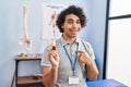 Hispanic man with curly hair holding cbd oil pointing finger to one self smiling happy and proud Royalty Free Stock Photo