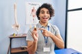 Hispanic man with curly hair holding cbd oil smiling happy pointing with hand and finger Royalty Free Stock Photo