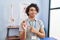 Hispanic man with curly hair holding cbd oil smiling happy pointing with hand and finger to the side Royalty Free Stock Photo