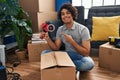 Hispanic man with curly hair moving to a new home closing cardboard box with tape smiling happy pointing with hand and finger Royalty Free Stock Photo