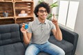 Hispanic man with curly hair playing colorful puzzle cube intelligence game surprised with an idea or question pointing finger Royalty Free Stock Photo