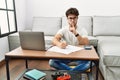 Hispanic man doing papers at home asking to be quiet with finger on lips Royalty Free Stock Photo