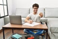 Hispanic man doing papers at home pointing to you and the camera with fingers, smiling positive and cheerful Royalty Free Stock Photo