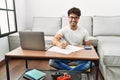 Hispanic man doing papers at home winking looking at the camera with sexy expression, cheerful and happy face Royalty Free Stock Photo