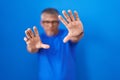 Hispanic man with grey hair standing over blue background doing frame using hands palms and fingers, camera perspective Royalty Free Stock Photo