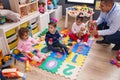 Hispanic man and group of kids having music class sitting on floor at kindergarten Royalty Free Stock Photo