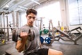 Hispanic man in gym sitting on bench, working out with weights Royalty Free Stock Photo