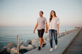 A Hispanic man and his girlfriend are strolling on a breakwater in Spain