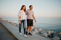 A Hispanic man and his girlfriend are strolling on a breakwater in Spain