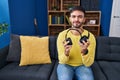 Hispanic man holding broken headphones relaxed with serious expression on face Royalty Free Stock Photo