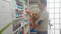 Hispanic man holding dog in a pharmacy checking medicine Royalty Free Stock Photo