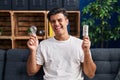 Hispanic man holding led lightbulb and incandescent bulb winking looking at the camera with sexy expression, cheerful and happy Royalty Free Stock Photo