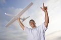 Hispanic man holding model airplane over head