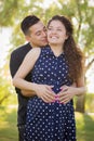 Hispanic Man Hugs His Pregnant Wife Outdoors At the Park Royalty Free Stock Photo