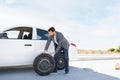 Hispanic man moving a spare tire next to his car Royalty Free Stock Photo