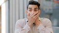 Hispanic man scared businessman boss stands in city covering mouth with hands from shock fear blab out secret frightened Royalty Free Stock Photo