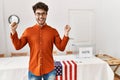 Hispanic man standing by election room celebrating surprised and amazed for success with arms raised and open eyes Royalty Free Stock Photo