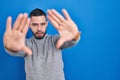 Hispanic man standing over blue background doing frame using hands palms and fingers, camera perspective Royalty Free Stock Photo