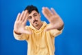 Hispanic man standing over blue background doing frame using hands palms and fingers, camera perspective Royalty Free Stock Photo