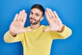 Hispanic man standing over blue background doing frame using hands palms and fingers, camera perspective Royalty Free Stock Photo