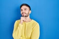 Hispanic man standing over blue background with hand on chin thinking about question, pensive expression Royalty Free Stock Photo