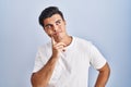 Hispanic man standing over blue background with hand on chin thinking about question, pensive expression Royalty Free Stock Photo