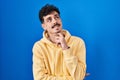 Hispanic man standing over blue background with hand on chin thinking about question, pensive expression Royalty Free Stock Photo