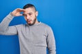 Hispanic man standing over blue background worried and stressed about a problem with hand on forehead, nervous and anxious for
