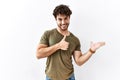 Hispanic man standing over isolated white background showing palm hand and doing ok gesture with thumbs up, smiling happy and Royalty Free Stock Photo